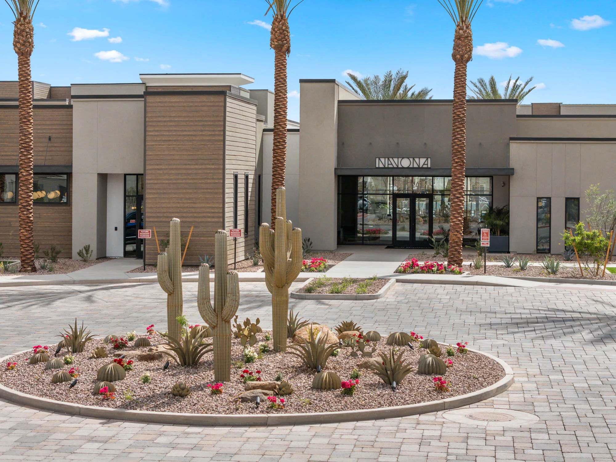 Apartment entrance with desert landscaping and saguaro cacti.