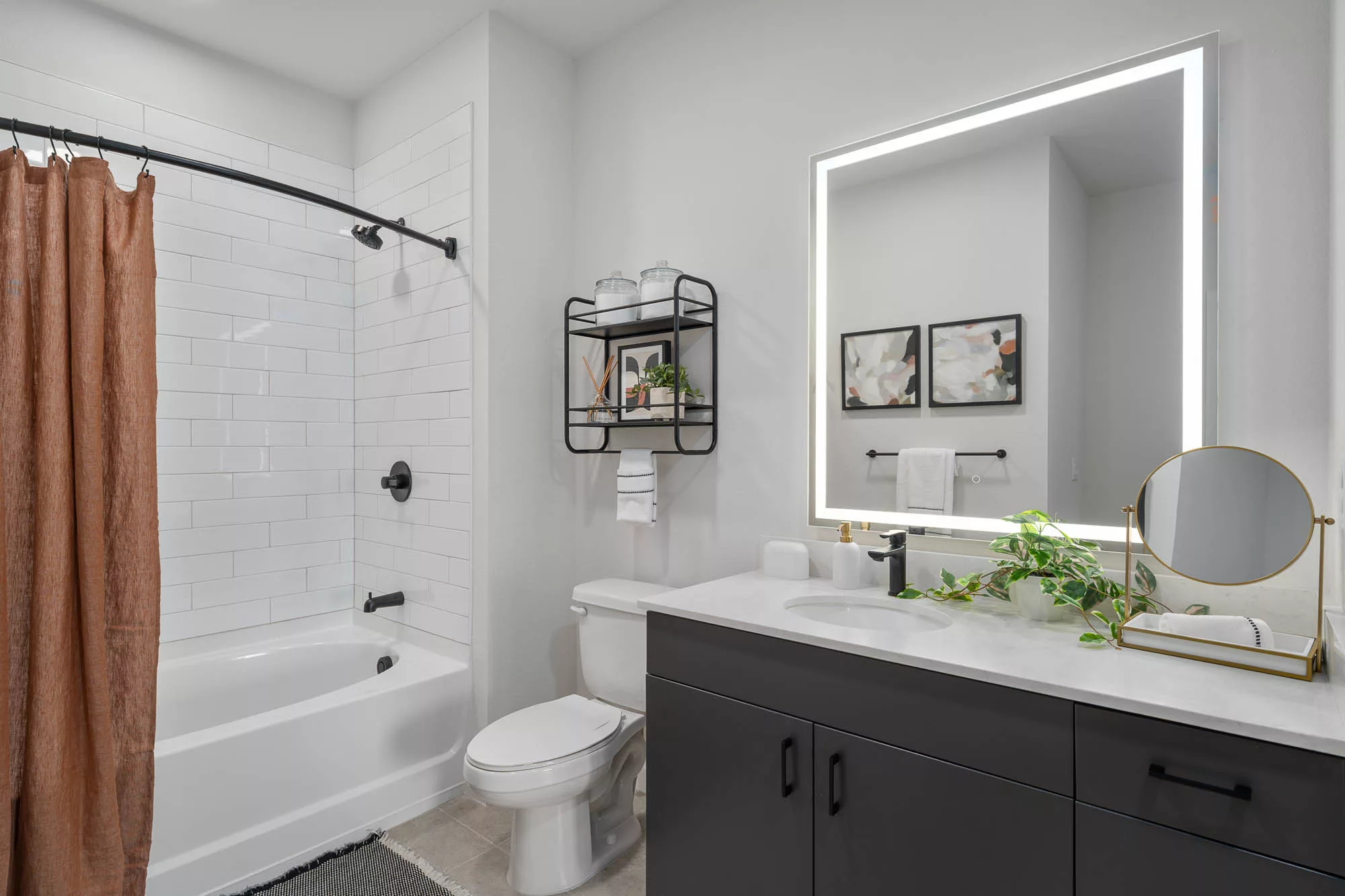 Bathroom with white tiled shower, large mirror, and black vanity.