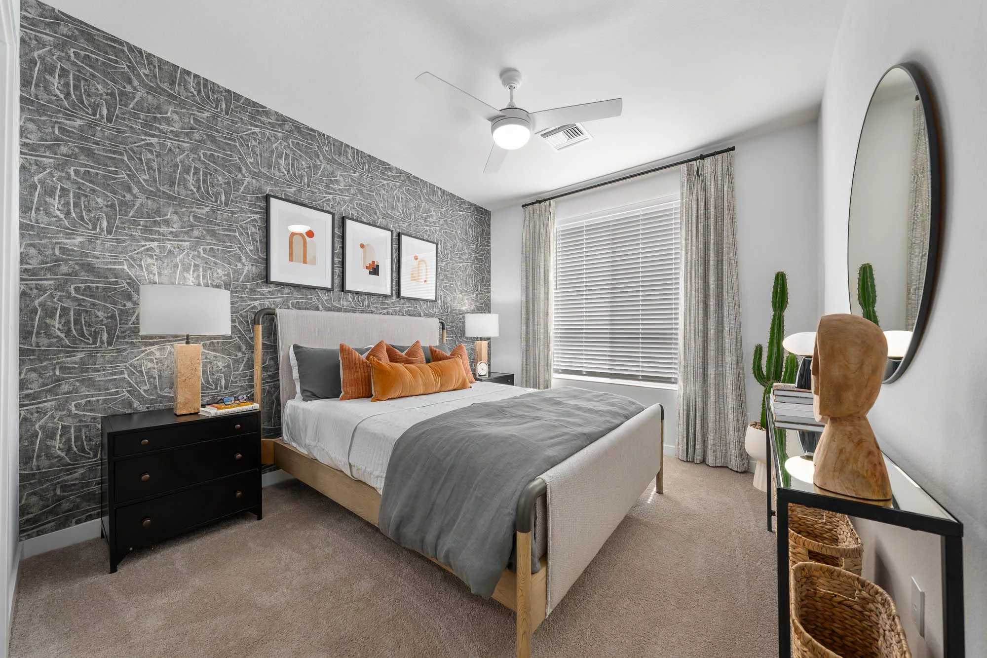 Bedroom with abstract wallpaper, orange pillows, and modern decor.