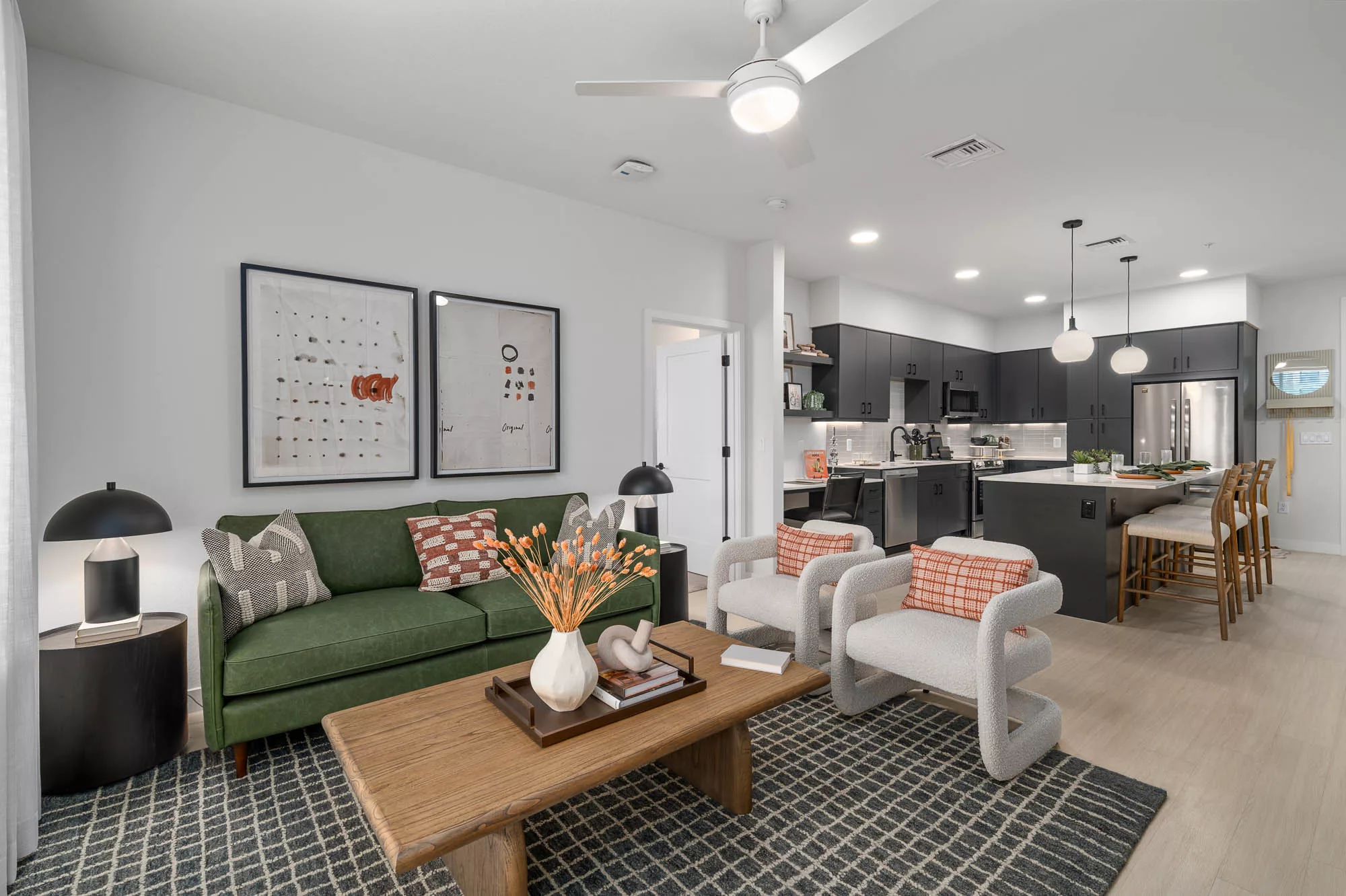 Open living area with green sofa and black kitchen cabinetry.