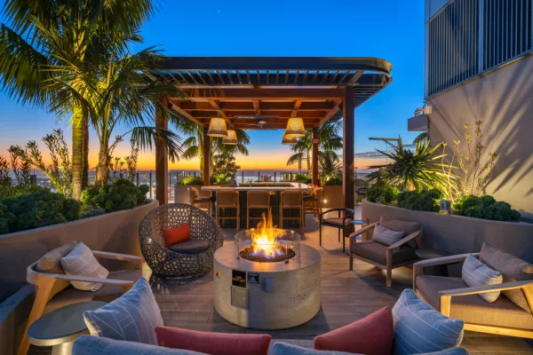 Outdoor lounge with firepit, tropical plants, and sunset view