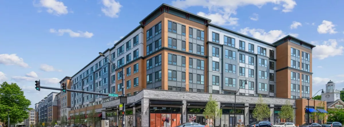 Modern mid-rise apartment building on a street corner with ground-floor retail.