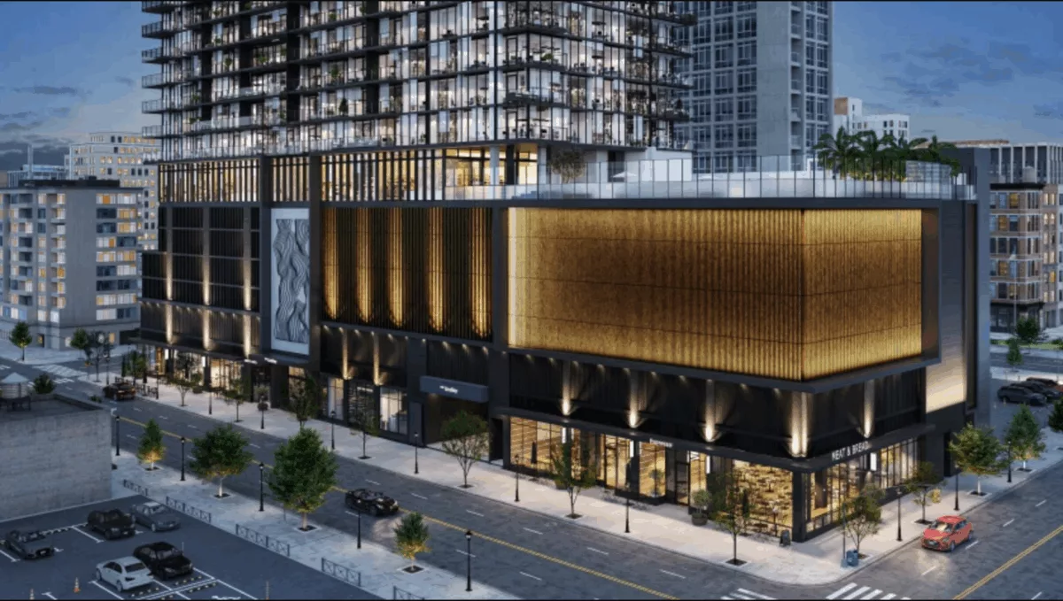 Modern mixed-use high-rise at night with glowing golden facade, street-level retail, and glass residential tower above
