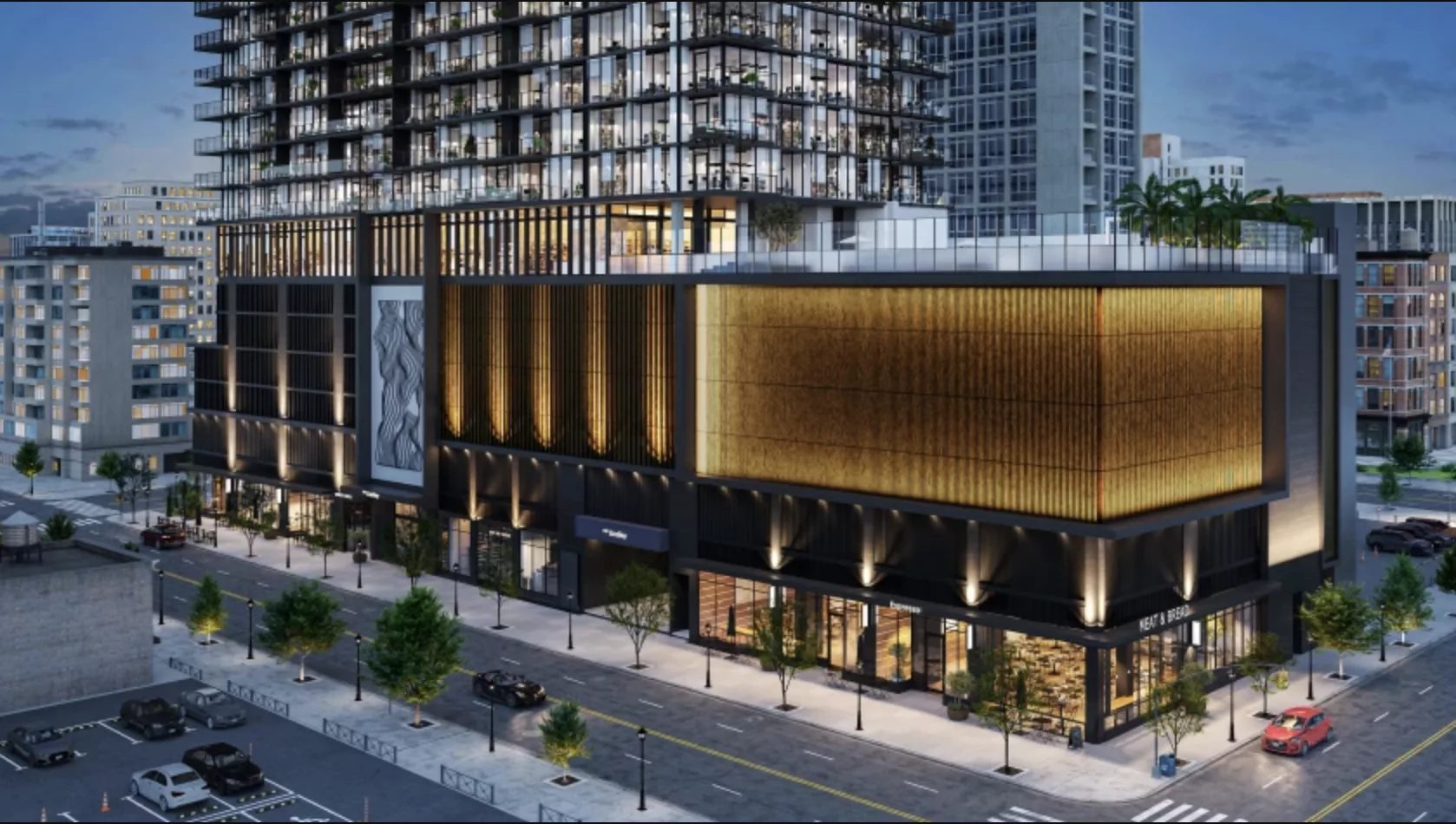 Modern mixed-use high-rise at night with glowing golden facade, street-level retail, and glass residential tower above