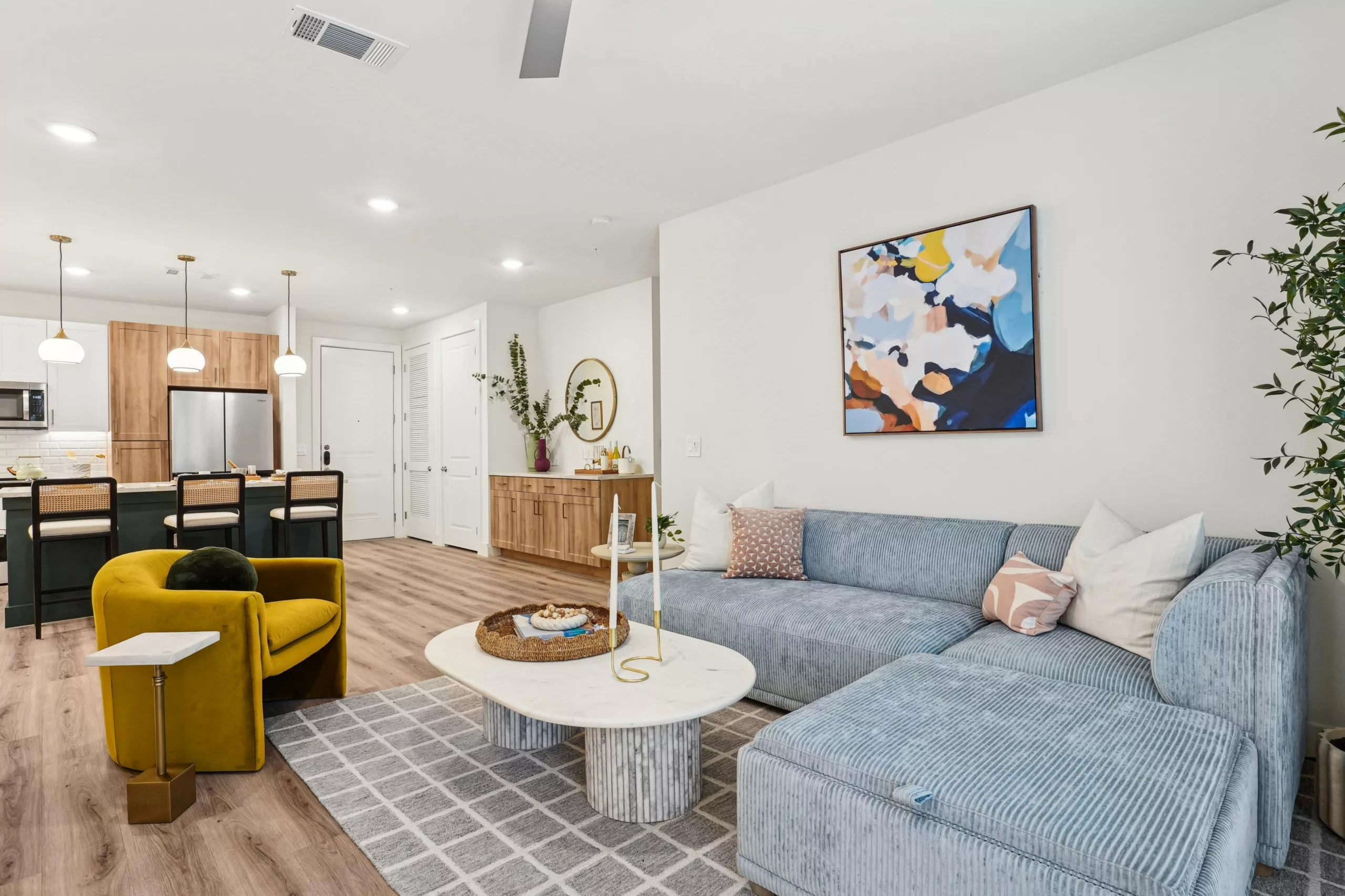 Living room with blue sectional, yellow chair, and abstract art.