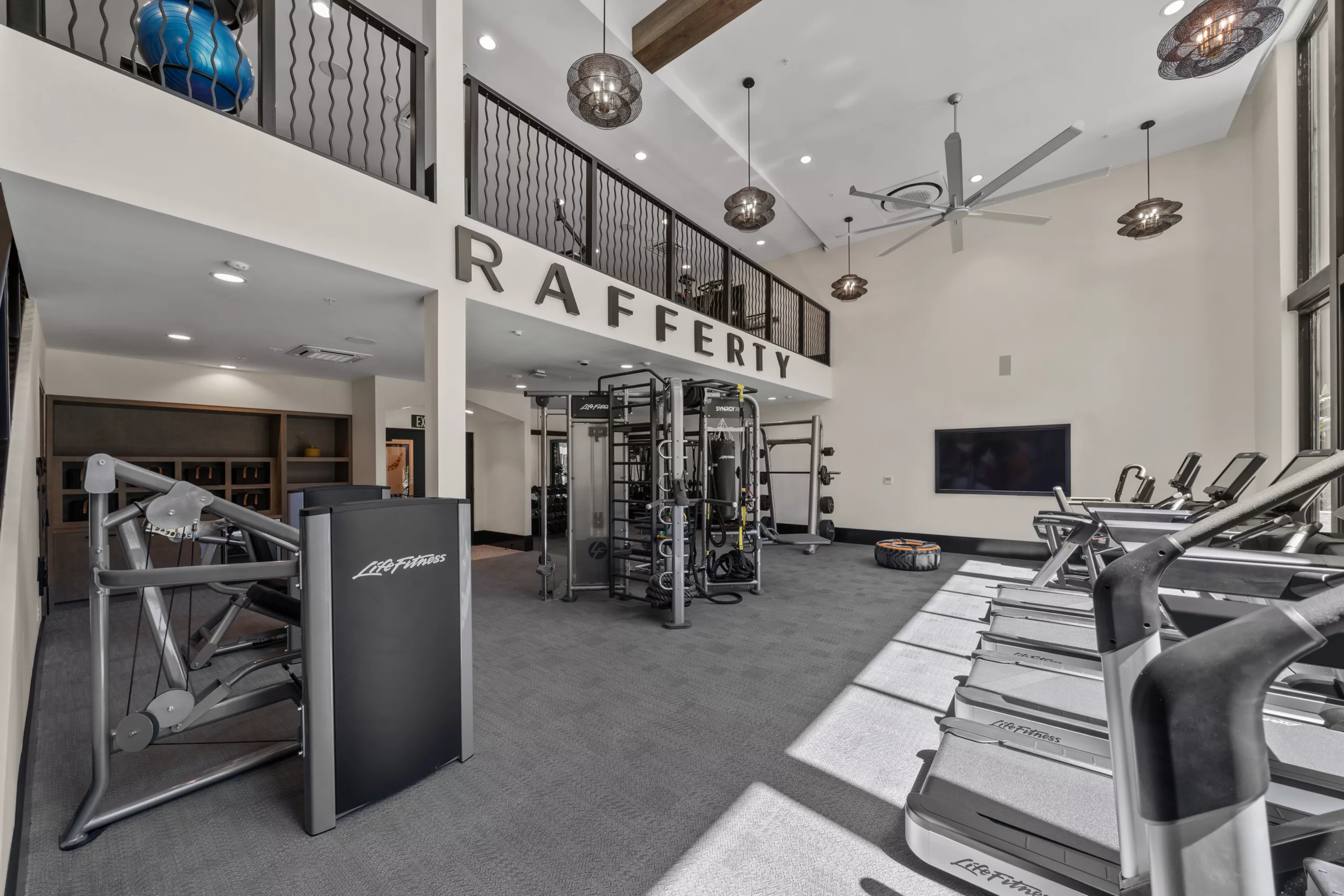 Fitness center with treadmills, strength equipment, and “RAFFERTY” sign.
