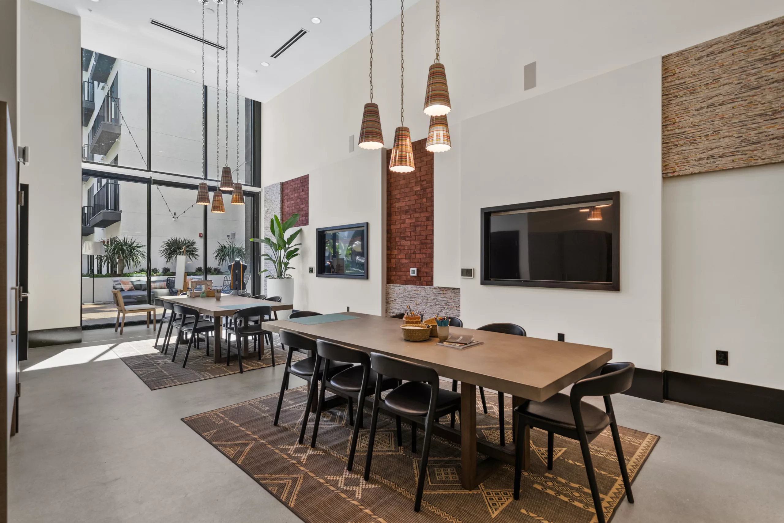 Bright coworking space with two long tables and pendant lights.