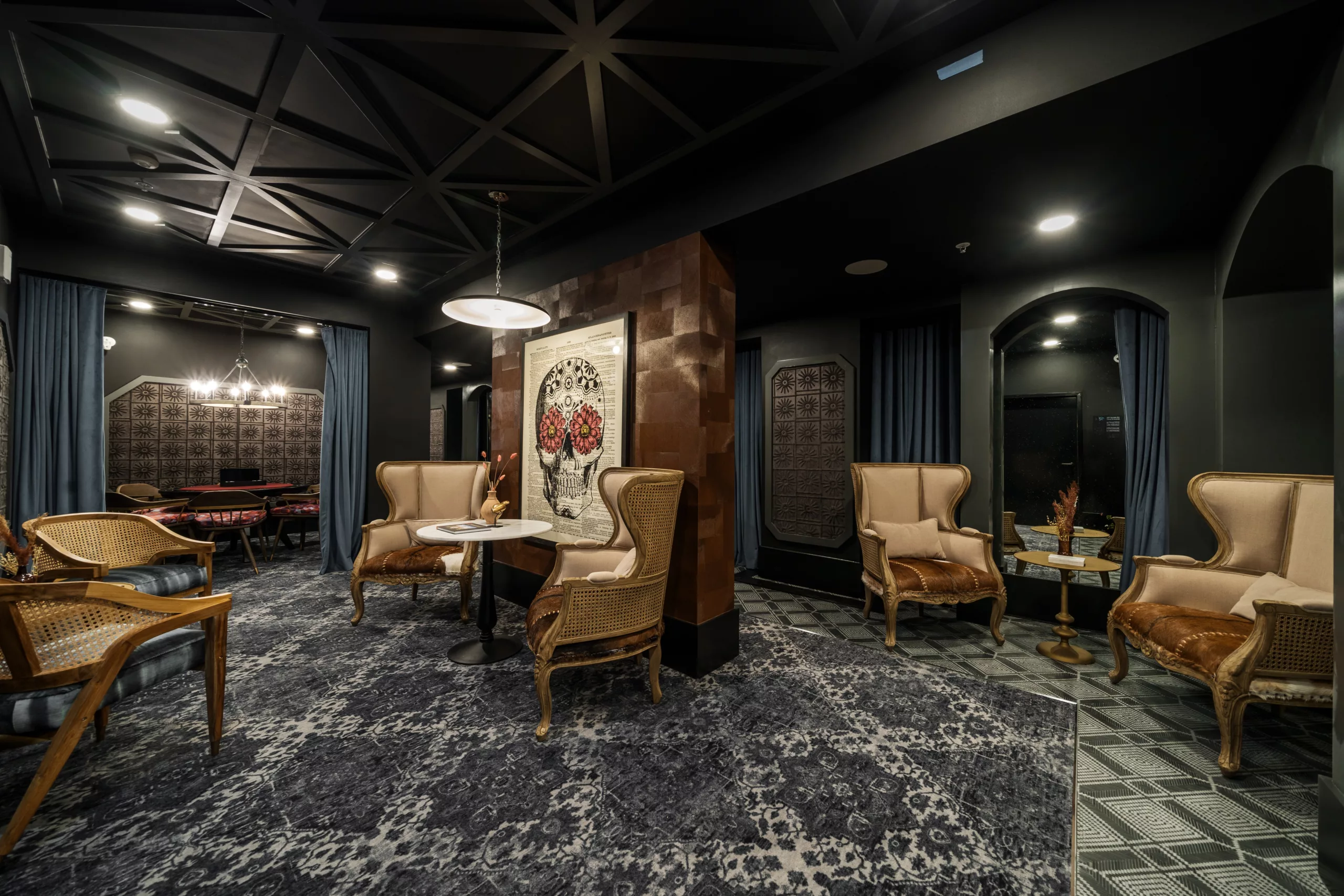 Dark lounge with ornate chairs, artwork, and dramatic lighting.