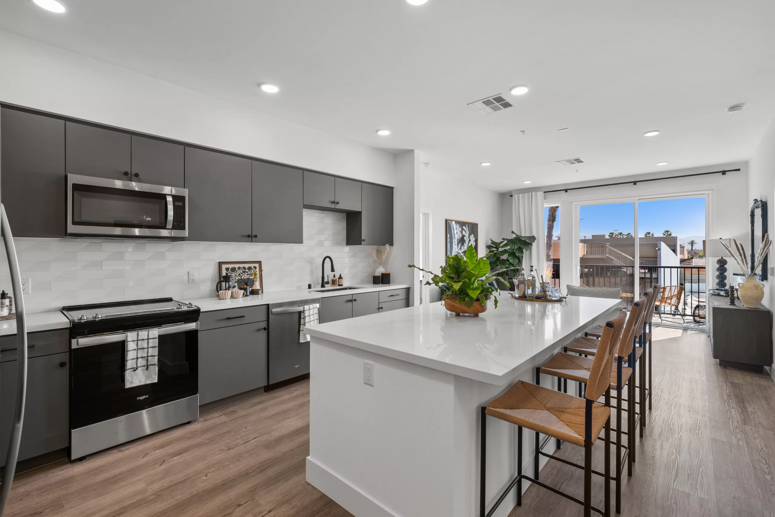 Open kitchen with island seating and sliding doors to balcony.