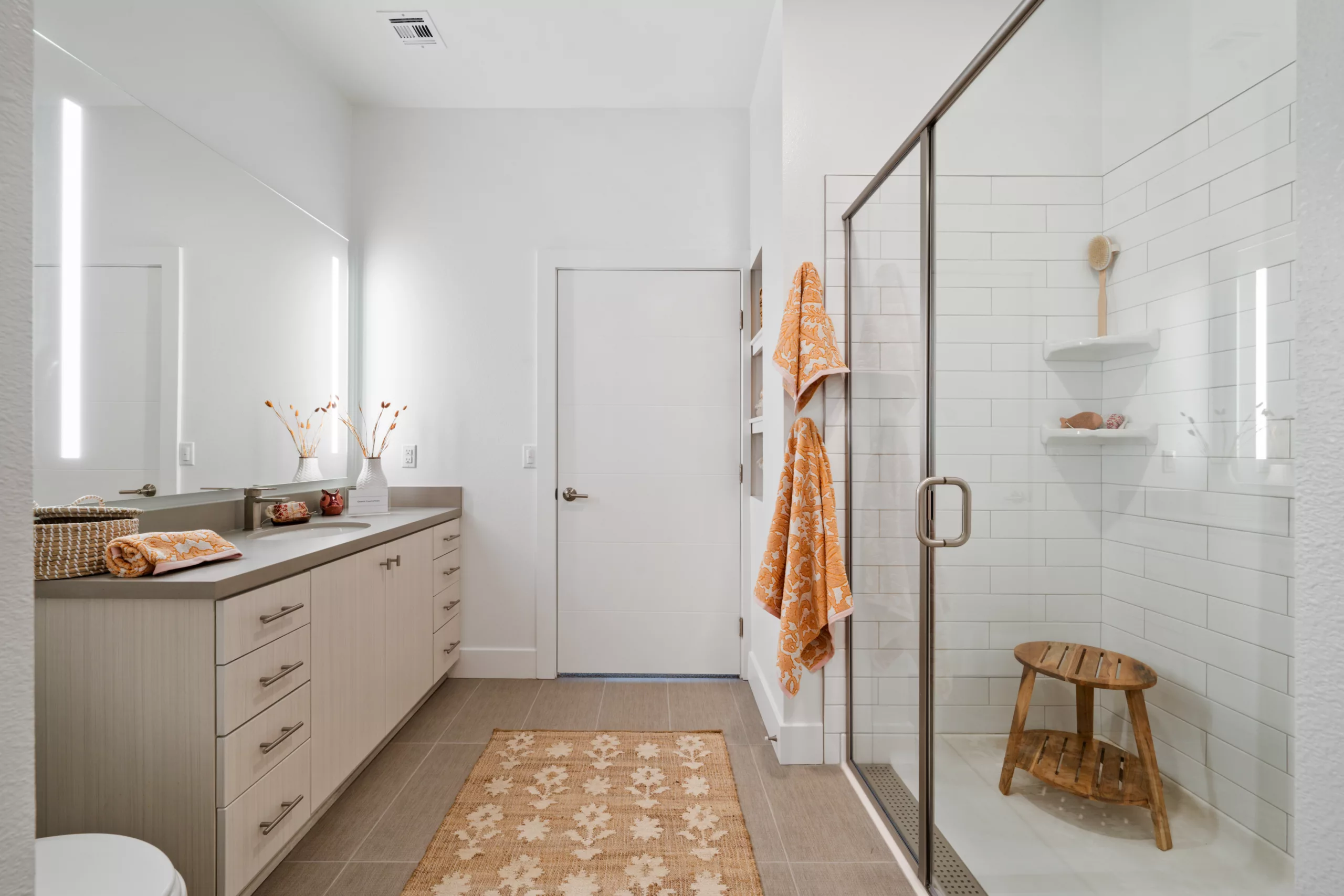 Bright bathroom with double vanity, large mirror, and walk-in glass shower.