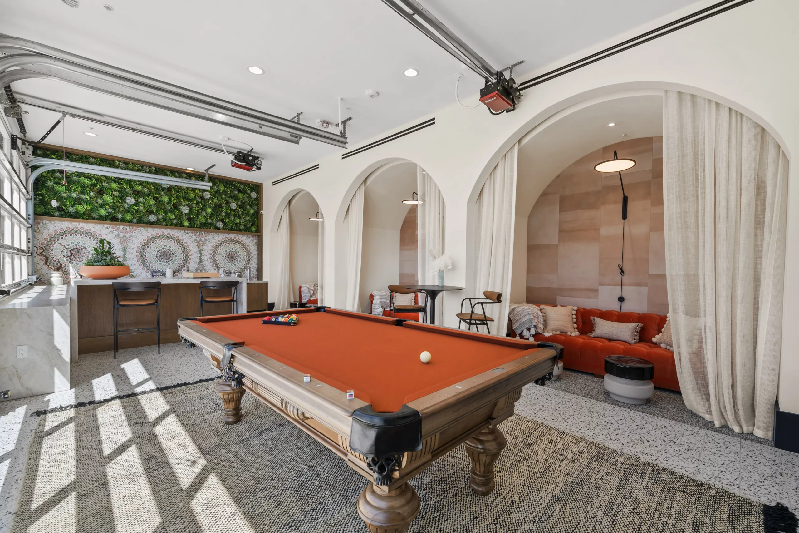 Recreation room with a red pool table, bar, and arched lounge nooks.