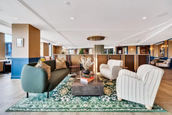 Lounge with green sofa, striped chairs, and floral rug in a modern common area