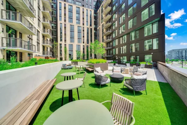 Outdoor terrace with green turf, seating areas, and high-rise buildings