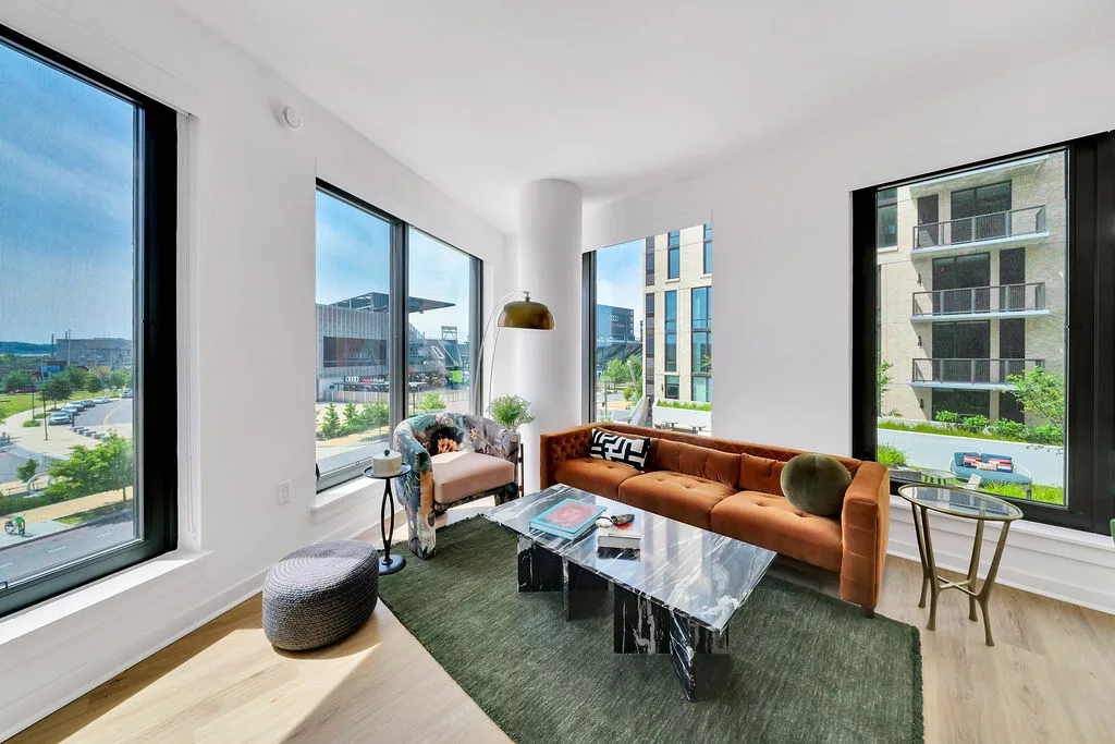 Bright living room with rust-colored sofa, black marble table, and city views