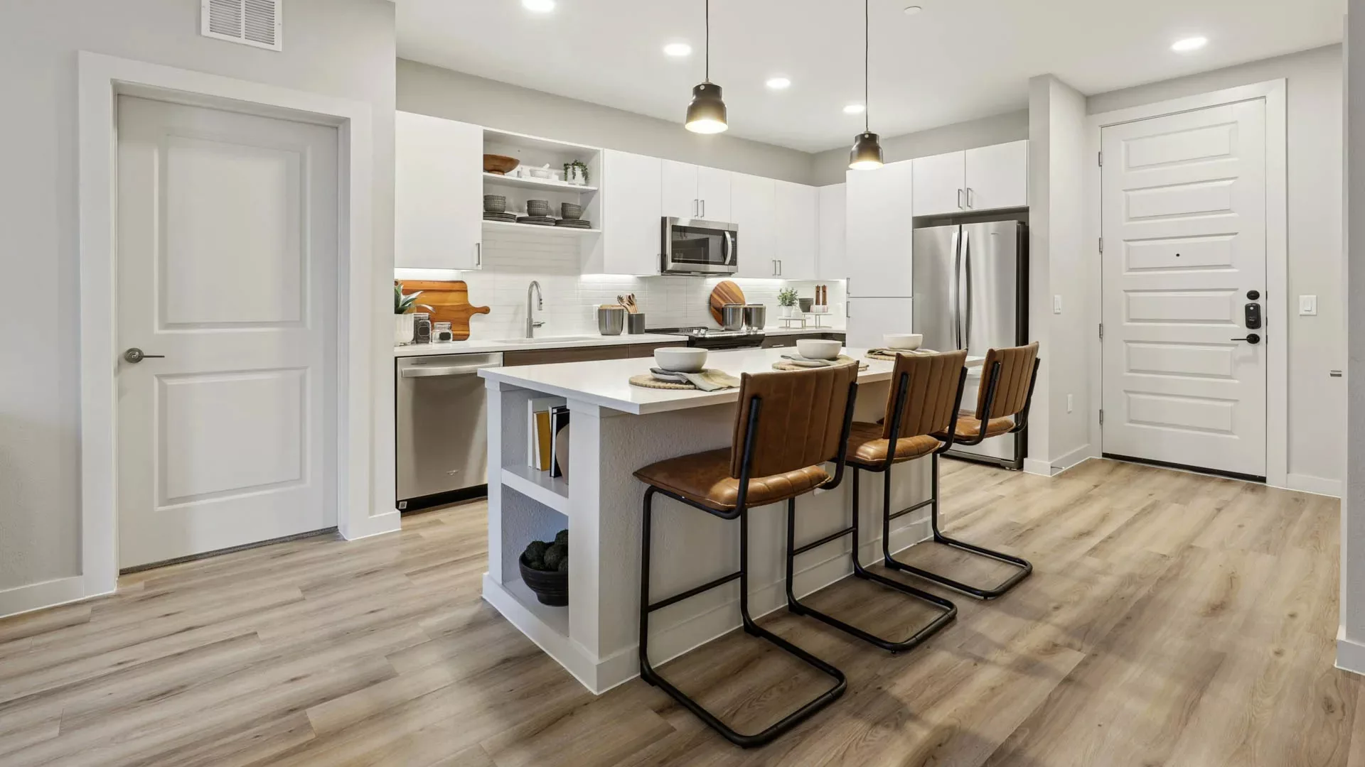 Modern kitchen with island seating, white cabinets, and wood flooring