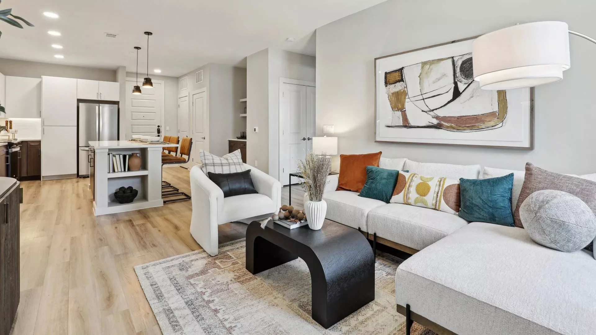 Open-plan living and kitchen area with light wood floors and abstract art