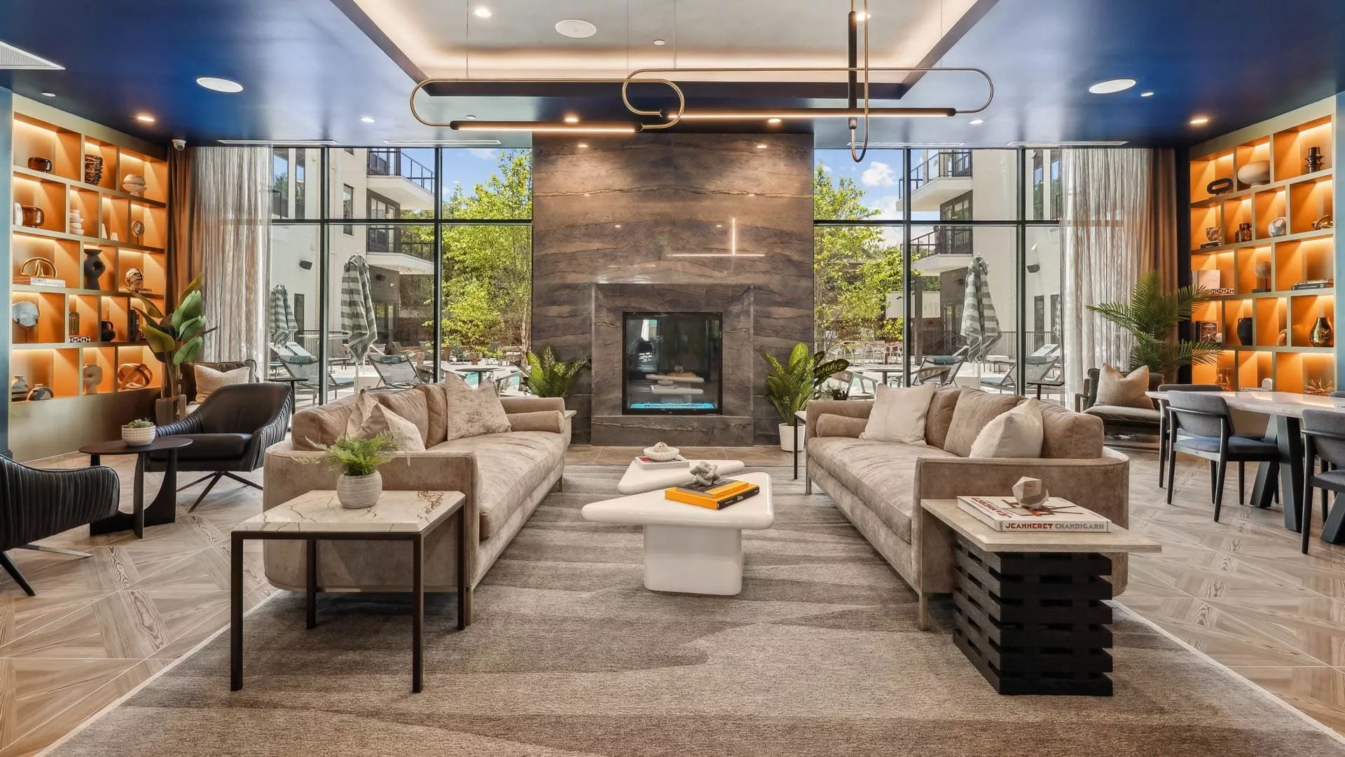 Lounge with sofas, fireplace, accent lighting, and pool view through glass wall