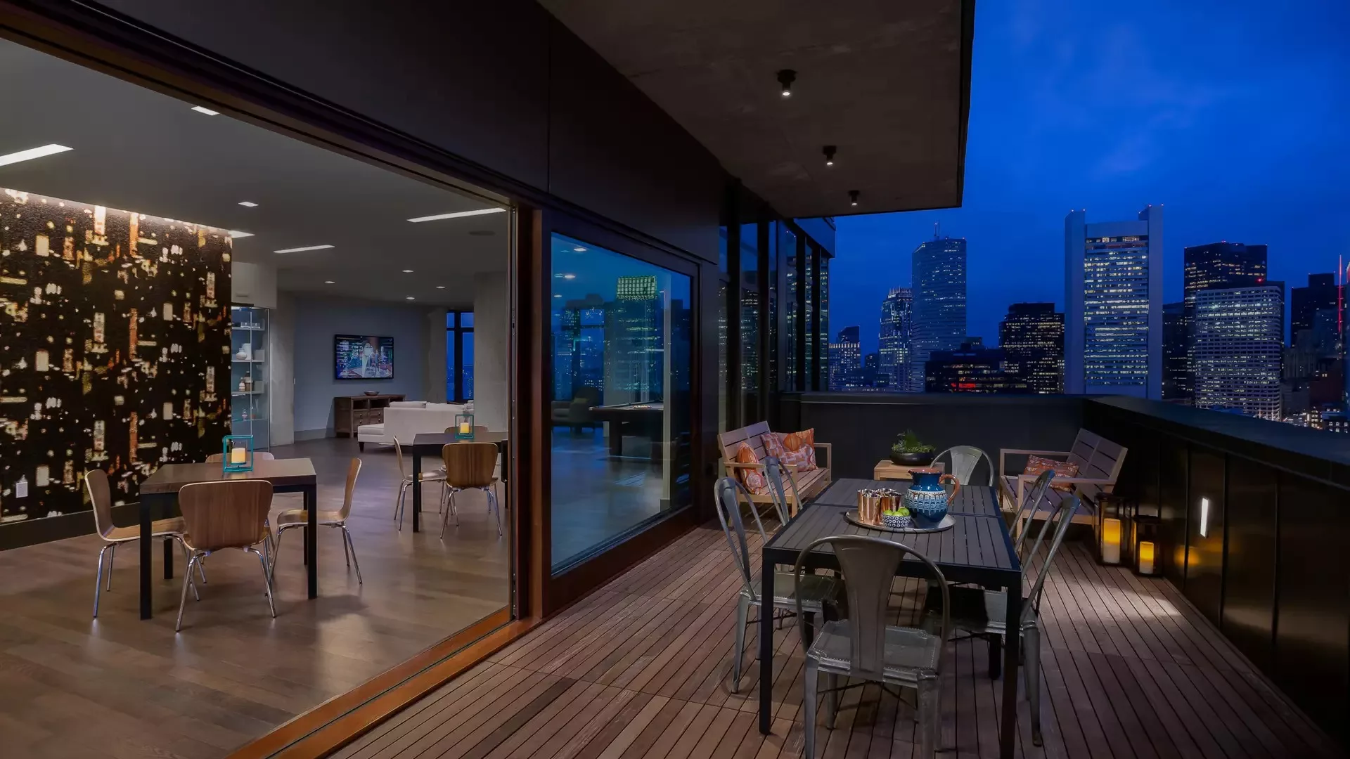 Rooftop patio with city skyline view and indoor lounge access