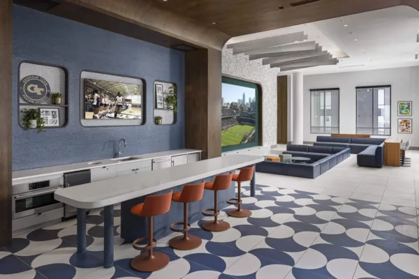Spacious lounge area with large TV screens, bar seating, modern decor, and blue-and-white geometric flooring.