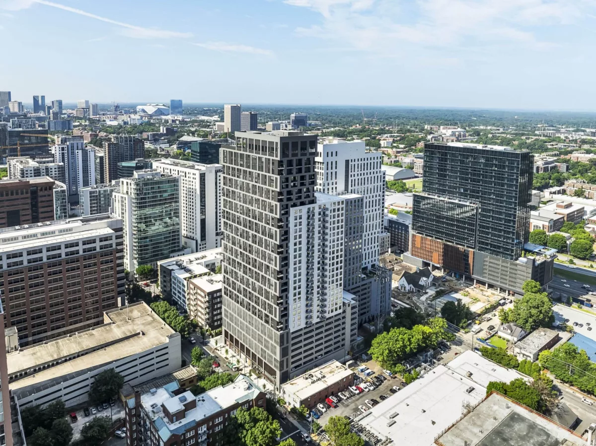 Aerial view of a modern high-rise apartment building surrounded by Atlanta’s cityscape and green areas.