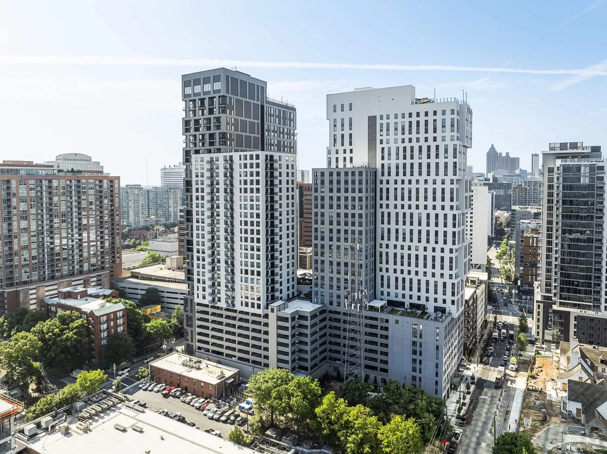 Cityscape of multiple high-rise apartment buildings in a dense downtown area with tree-lined streets and other towers.
