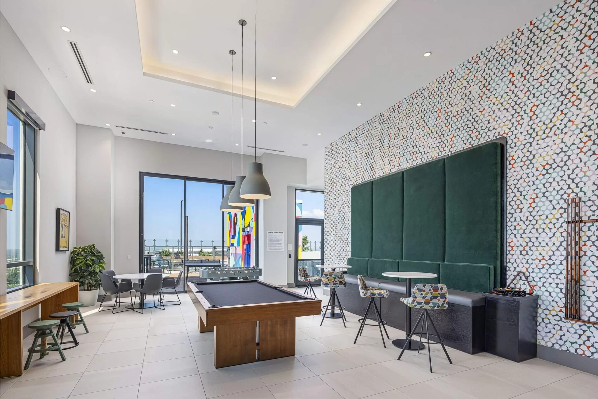 Game and lounge area with pool table, foosball table, colorful modern decor, and access to outdoor terrace.