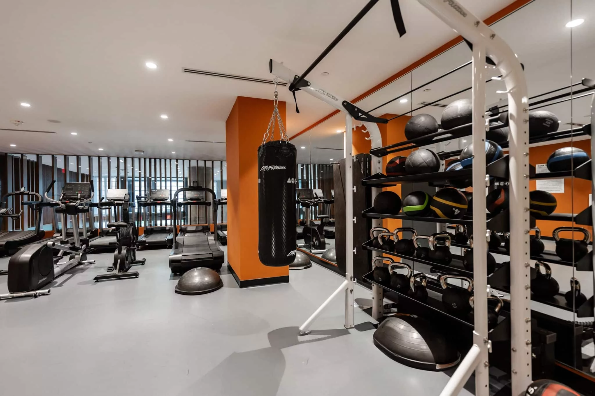 Fully equipped gym with treadmills, weight machines, kettlebells, and a punching bag in a modern fitness center.