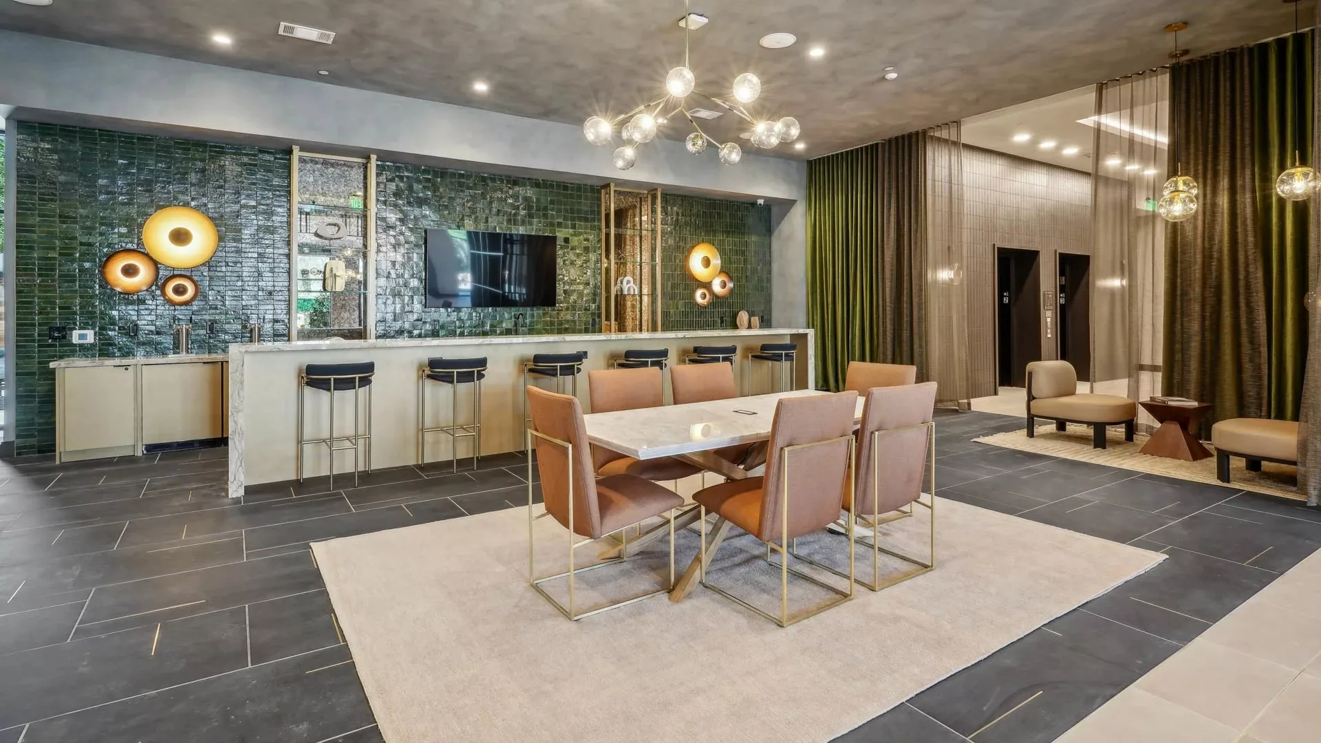 Lounge with green tile bar wall, dining table, and modern lighting