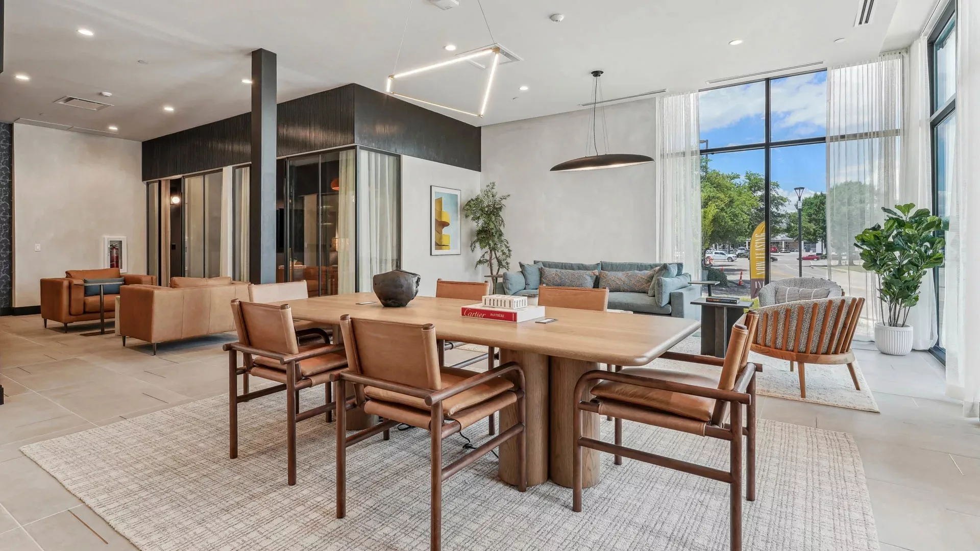 Lounge with wood dining table, leather chairs, and large windows