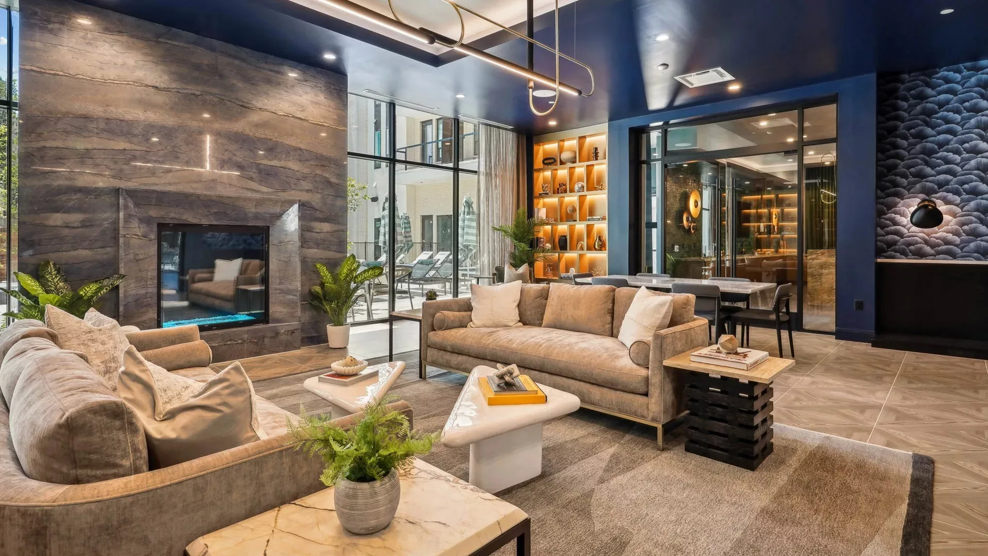Modern lounge with velvet sofas, fireplace, and bold blue walls
