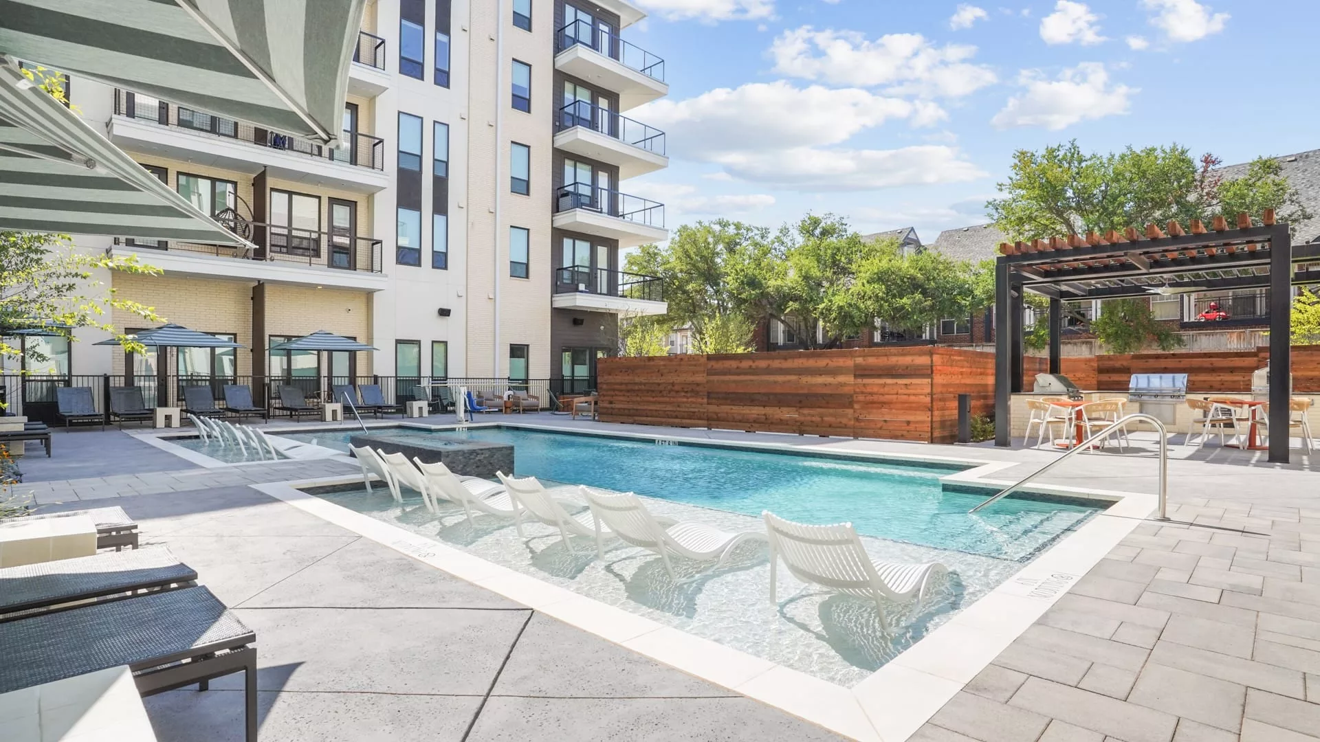 Swimming pool with in-water loungers and covered grill area nearby
