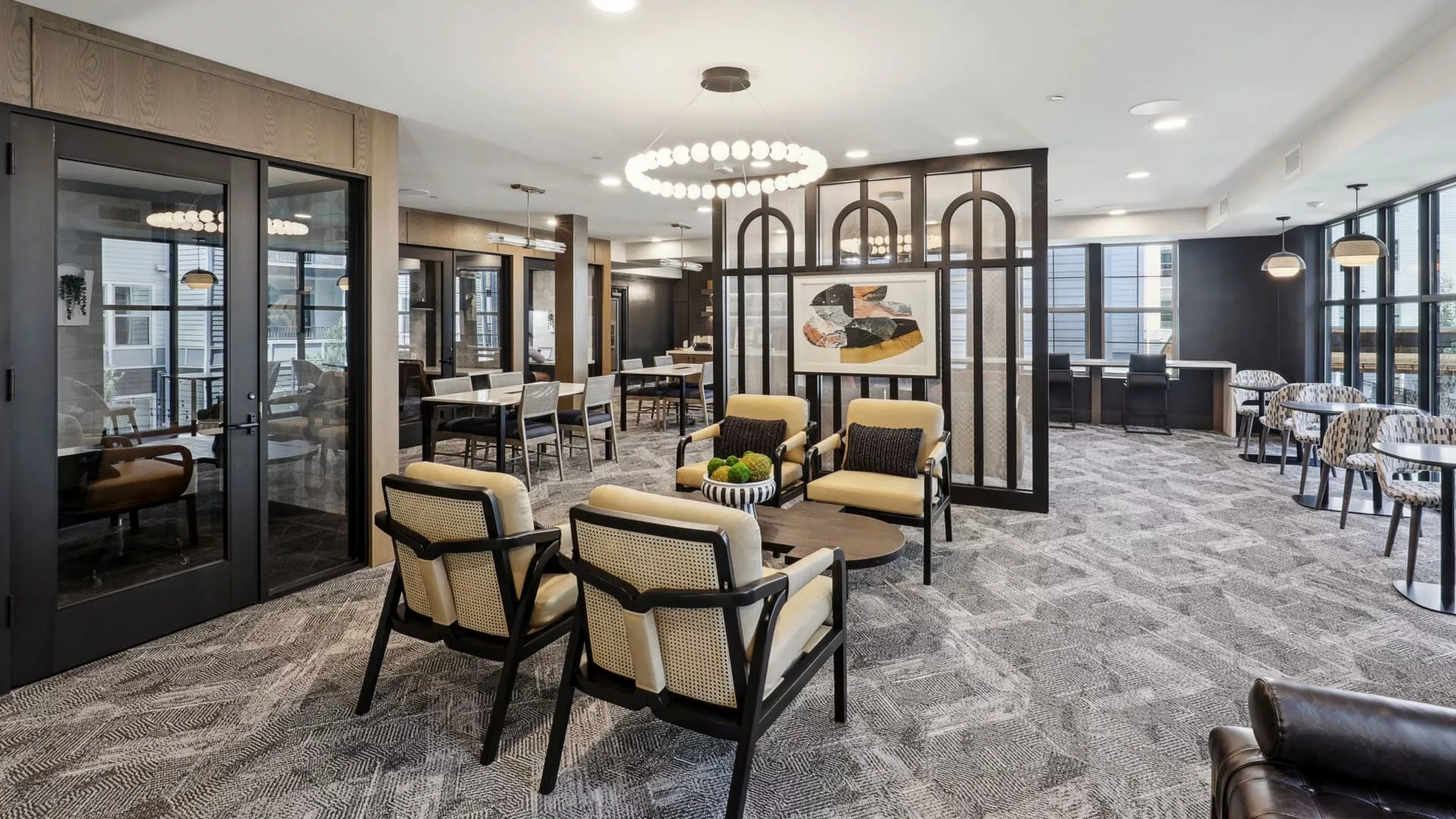 Lounge area with modern chairs, tables, and large ring chandelier