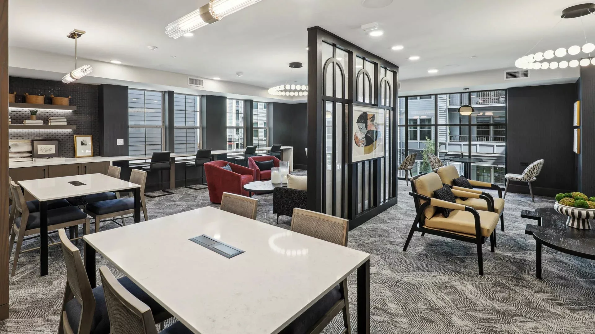 Coworking lounge with modern tables, seating areas, and windowed partitions