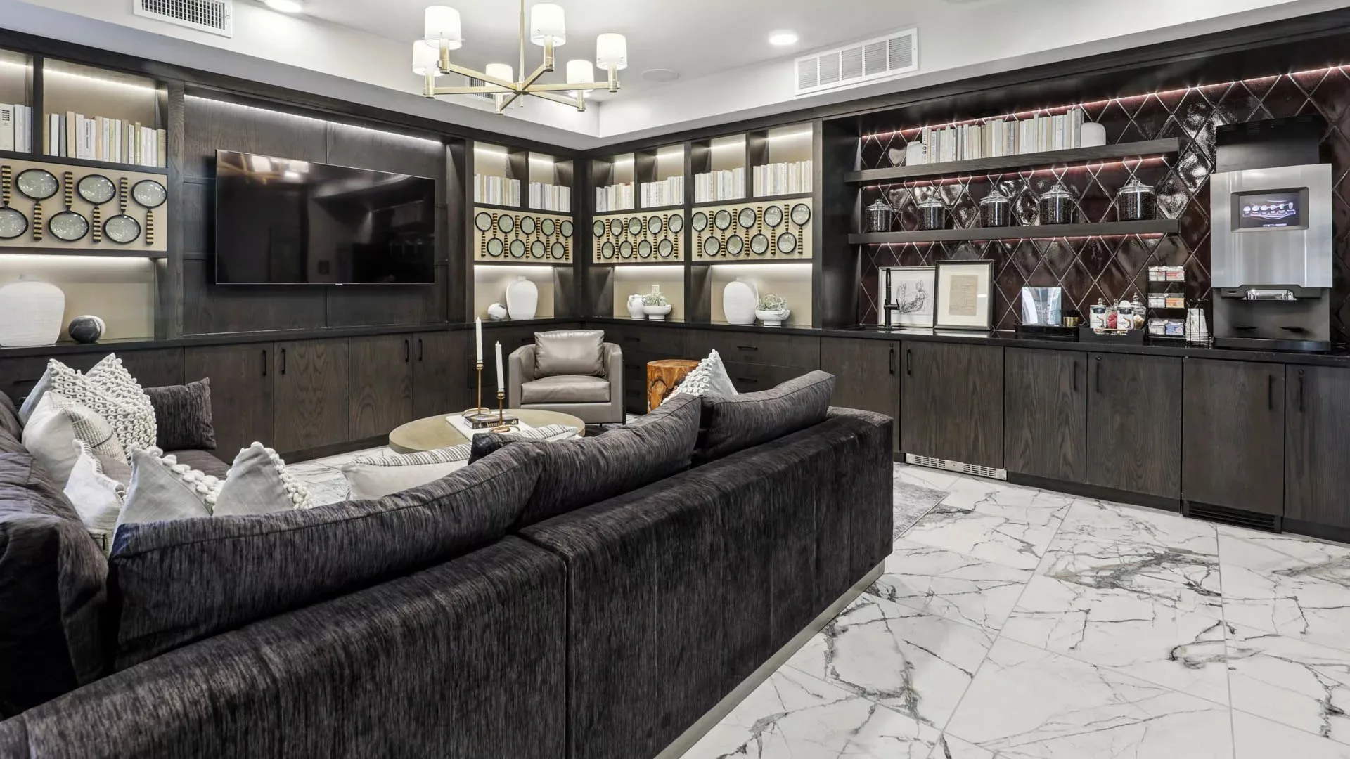 Lounge with sectional sofa, TV, bookshelves, and marble tile flooring
