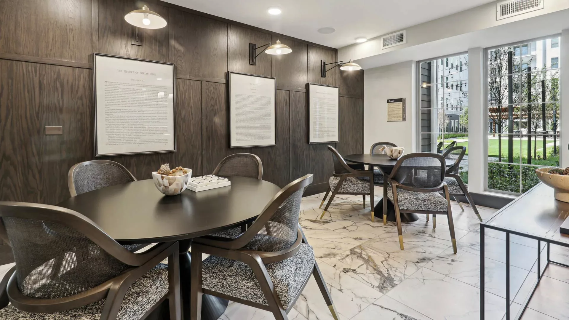 Library-style room with round tables, wall art, and courtyard view