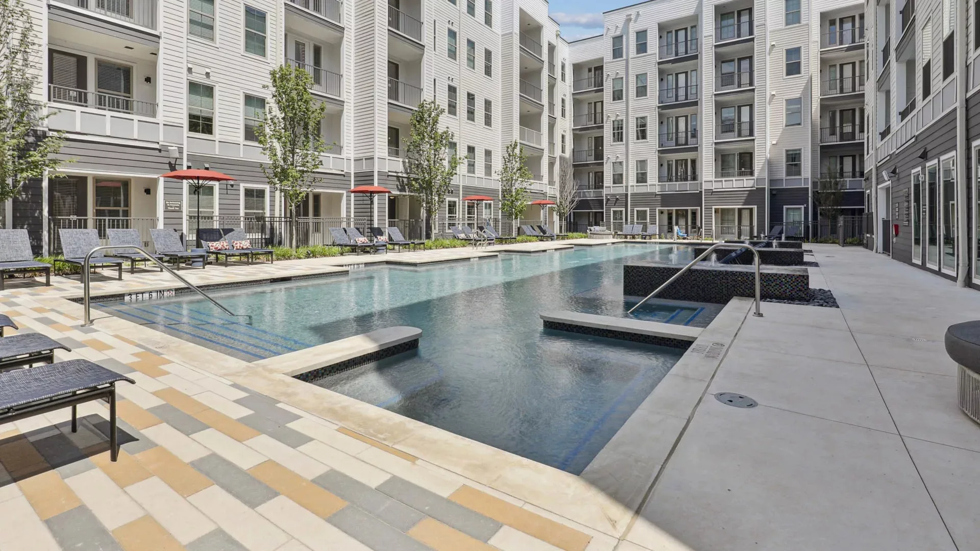 Outdoor pool surrounded by lounge chairs and apartment buildings