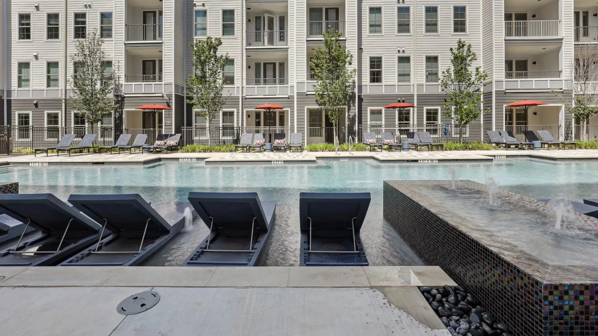 Poolside loungers in shallow water facing central apartment courtyard