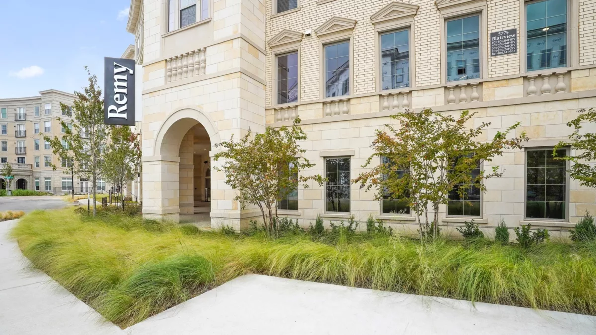 Exterior of Remy building with stone façade and landscaped walkway