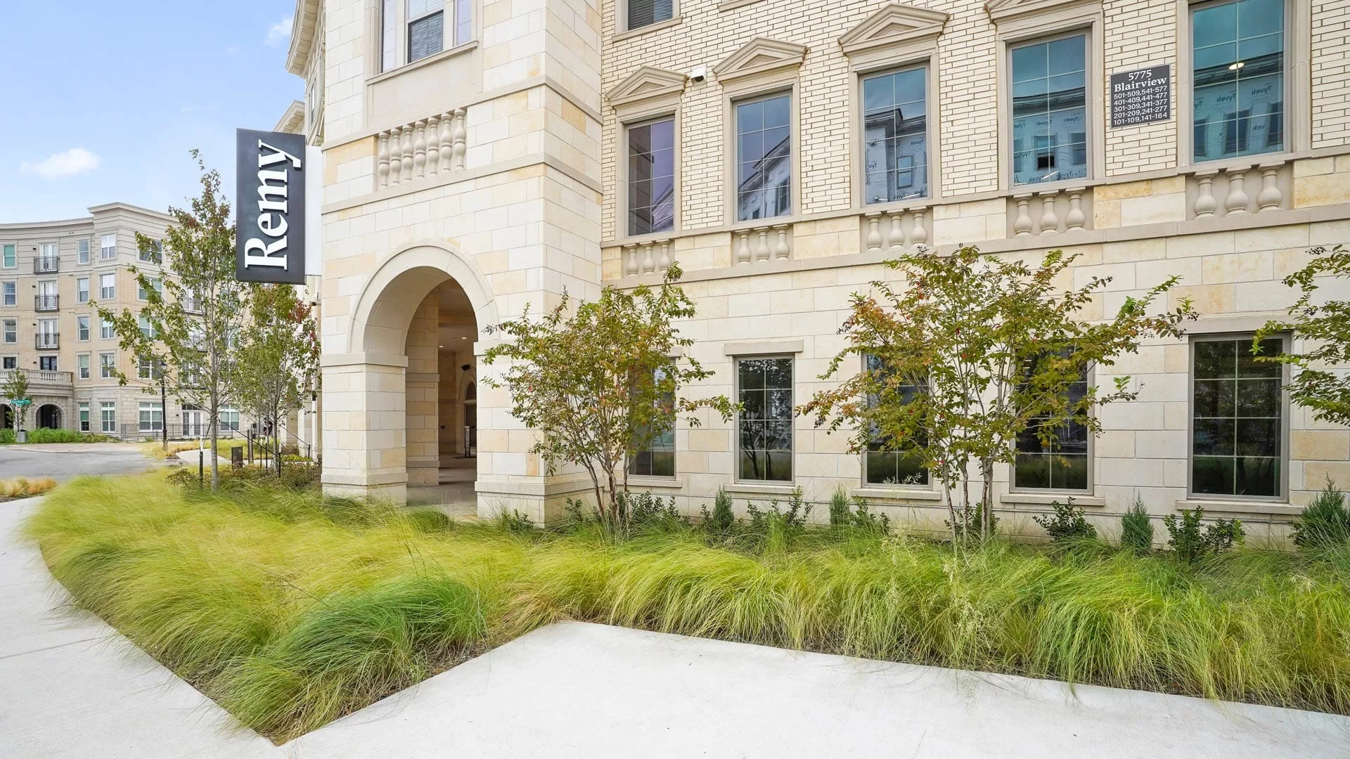 Exterior of Remy building with stone façade and landscaped walkway