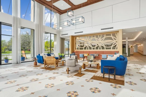 Spacious lobby with tall windows, modern furniture, and geometric floor tiles