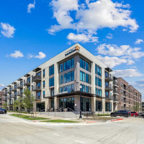 Modern four-story apartment building with large windows and street-facing entrance