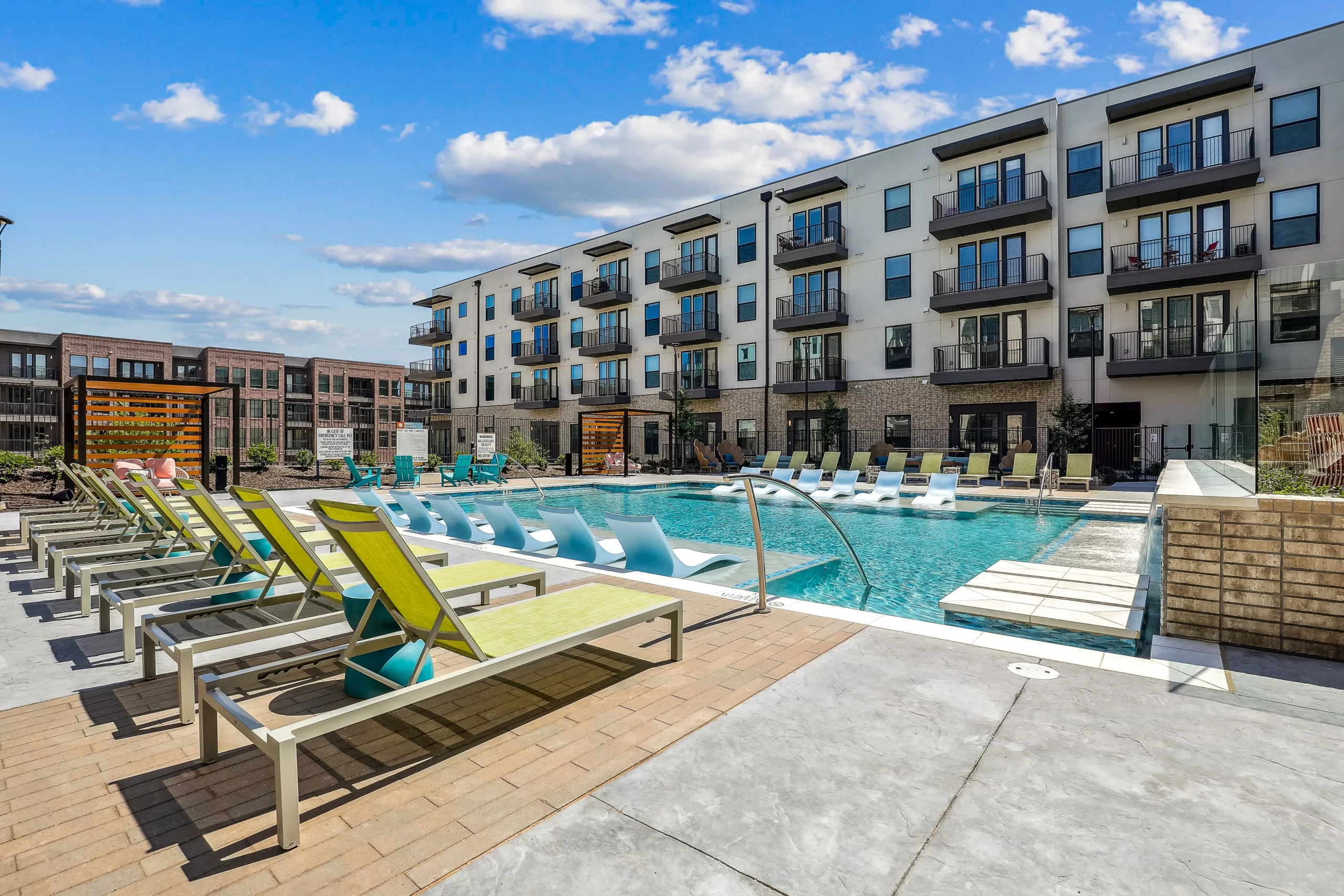 Outdoor pool area with lounge chairs and four-story apartment backdrop