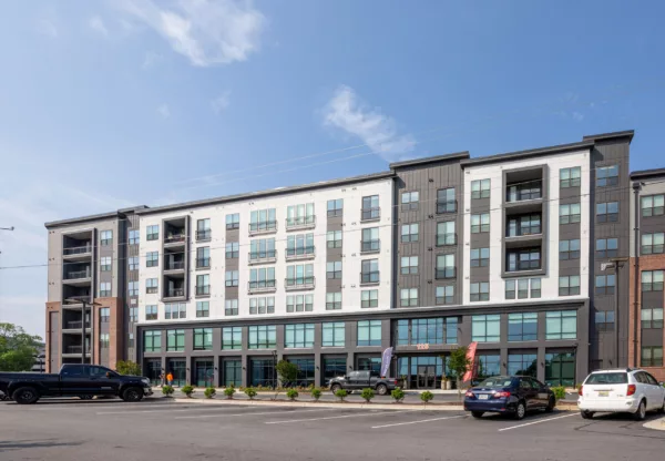 Modern mid-rise apartment building with balconies and ground-floor retail.