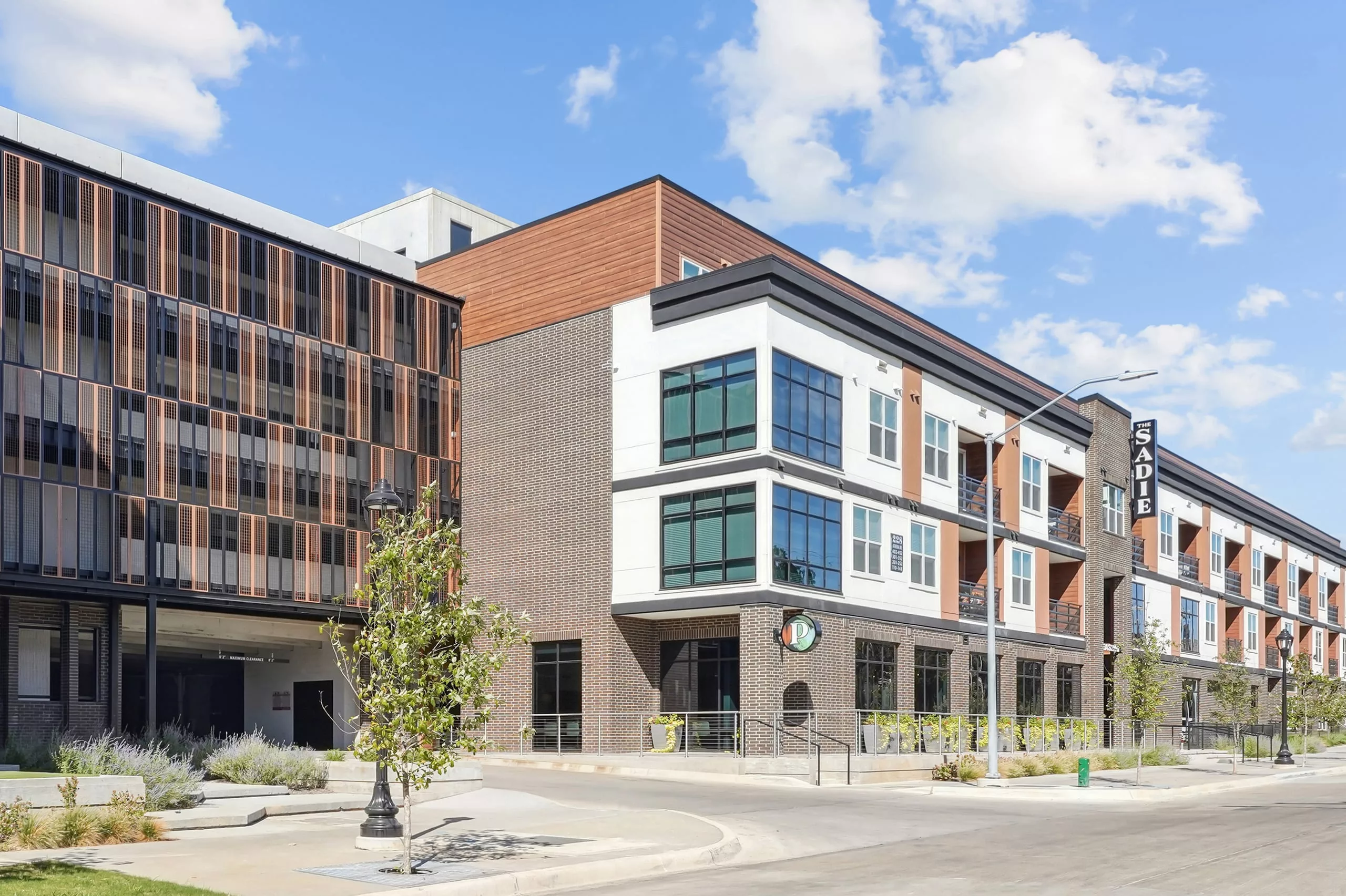 Modern mixed-use building with “The Sadie” sign, large windows, and brick and wood accents.