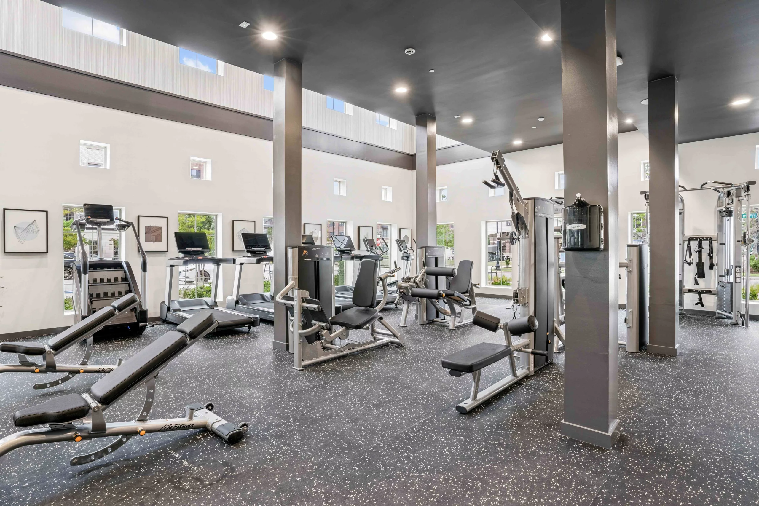 Fitness center with treadmills, weight machines, and rubber flooring.