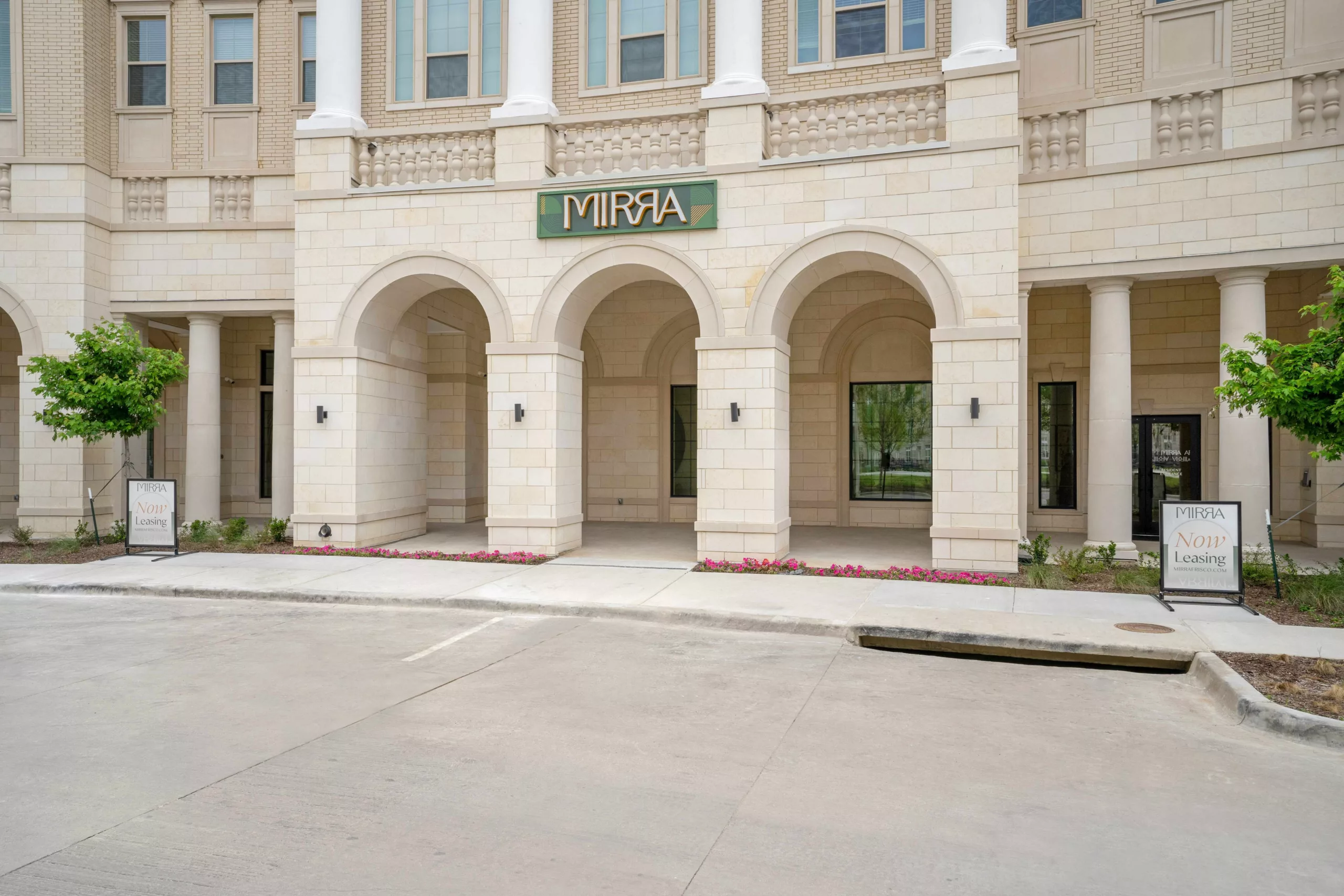 Building facade with arched entryway, columns, and stone detail with a sign that says "Mirra".