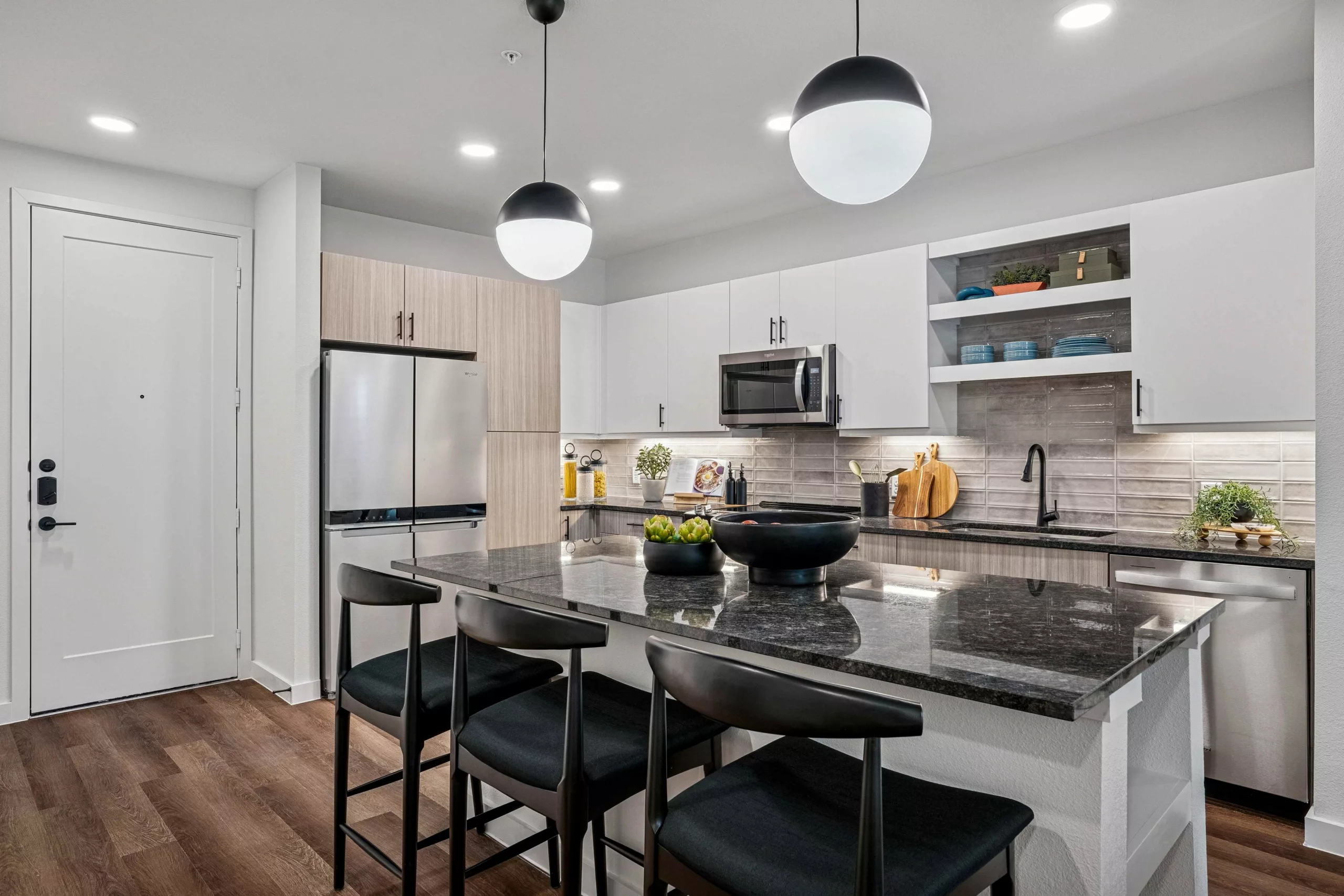 Modern kitchen with granite island, stainless steel appliances, and pendant lighting.