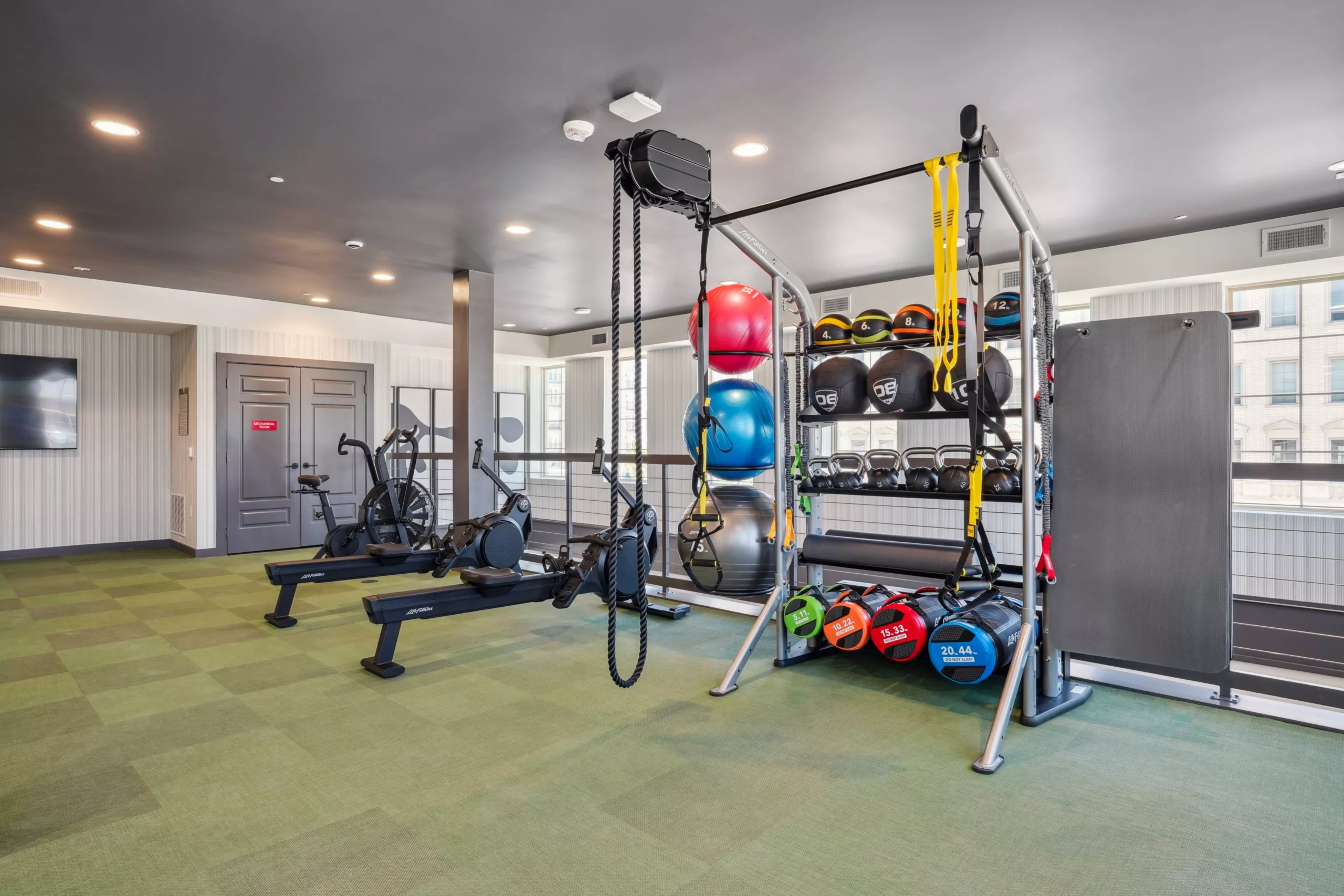 Fitness center with rowing machines, medicine balls, kettlebells, and exercise mats.