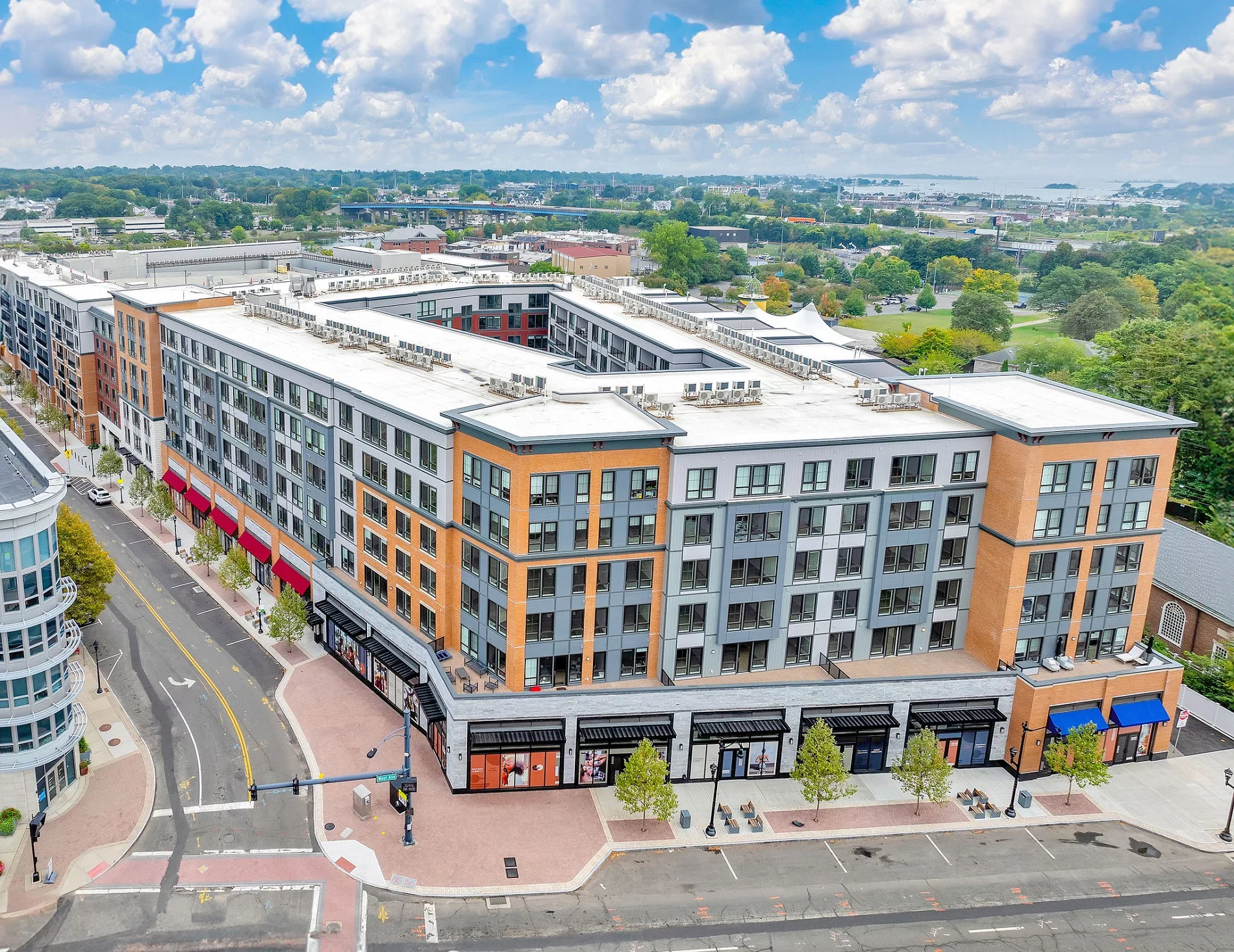 Aerial view of a multi-story apartment building with retail space on the ground floor.
