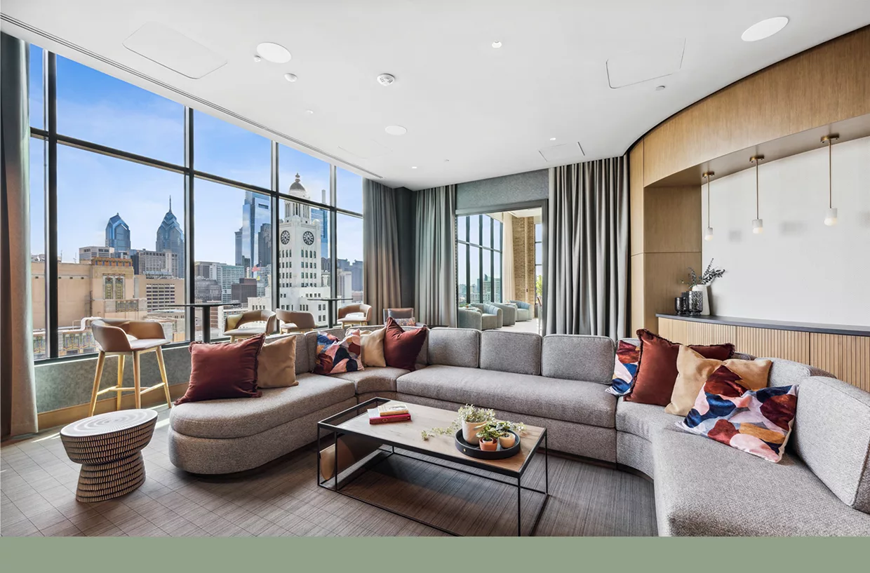 Large sectional sofa, bar seating, and city skyline through tall windows